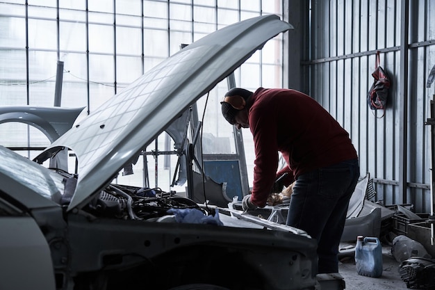 Photo car service worker repairs restores car