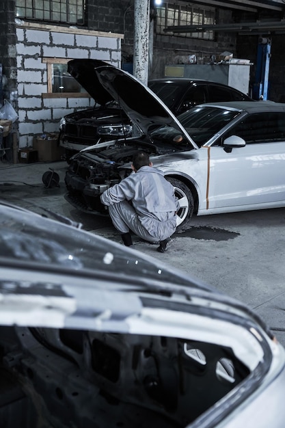 Car service worker repairs restores car