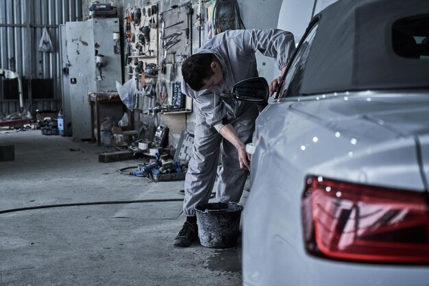 Car service worker repairs restores car