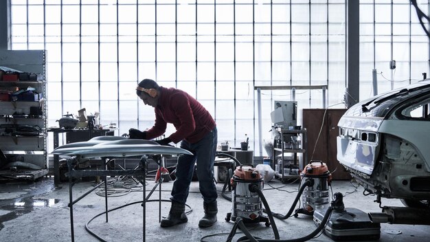 Car service worker repairs restores car