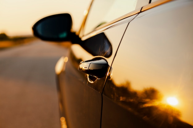 Car side on the background of sunset reflexion