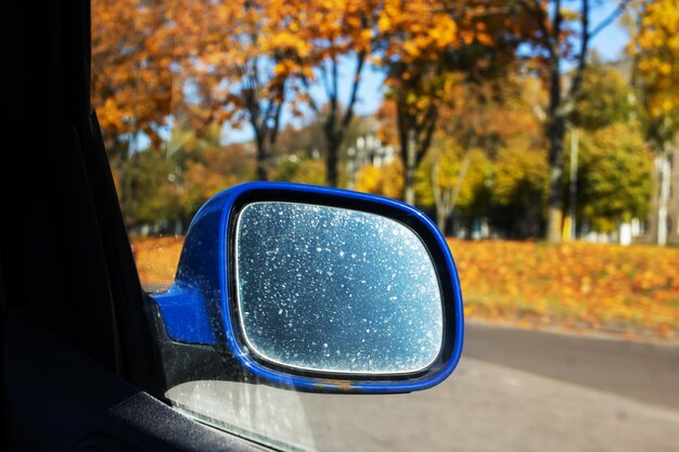 Foto specchietto laterale auto sullo sfondo della strada autunnale