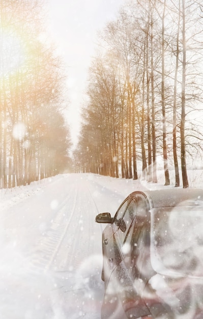 野原で雪に覆われた冬の道を走る車。