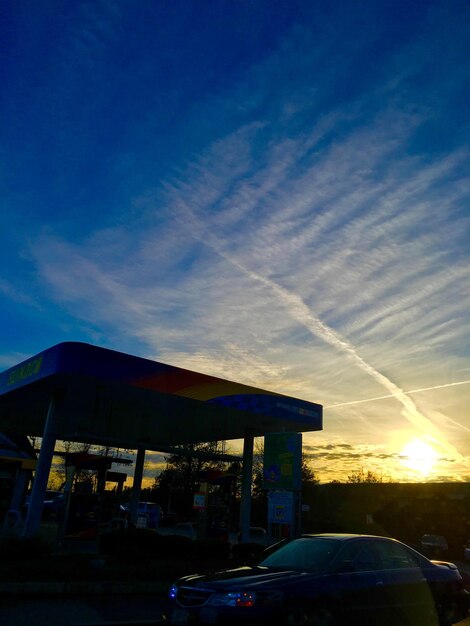 Photo car on street by building against sky during sunset