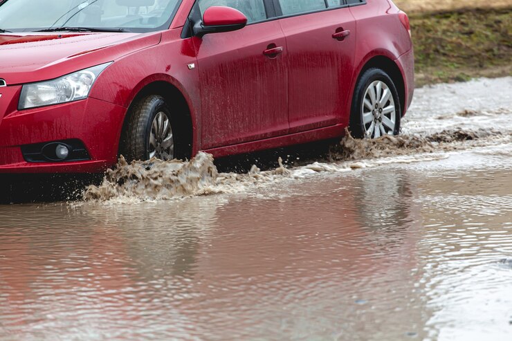 車が泥の中に詰まっている、車のホイールが汚れた水たまりにある、起伏の多い地形