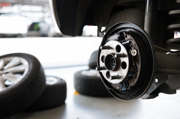 自動車整備における自動車の懸架と車輪ハブの支承車は油圧で持ち上げ、ガレージでタイヤの交換を待っています。パンチホイールのコンセプト