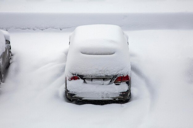 厚い雪の層の下の車 冬の吹雪の間に雪に覆われた車