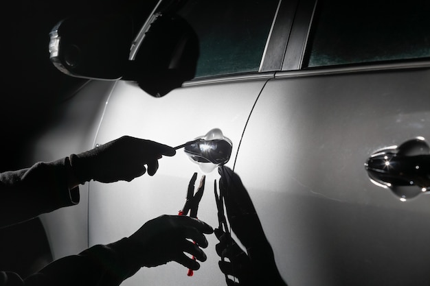 Car thief using a tool to break into a car