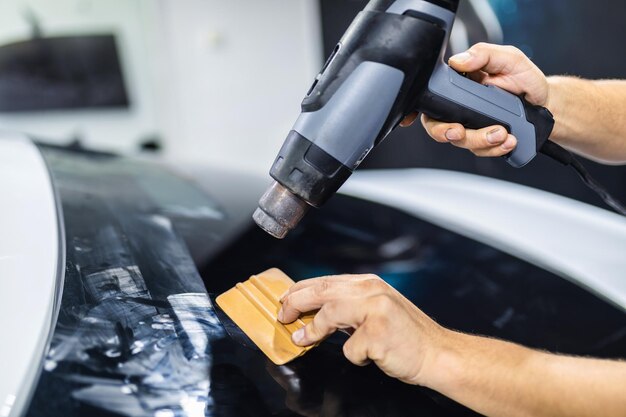 Car tinting - Worker applying tinting foil on car window.