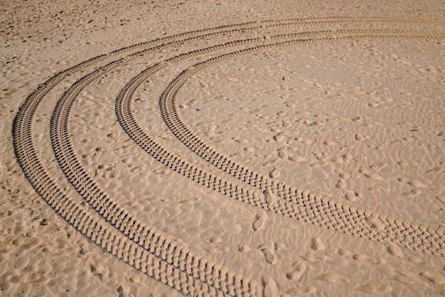 사막 모래 언덕의 고운 모래에 있는 사막 해변의 모래에 있는 자동차 타이어 발자국과 바퀴 자국