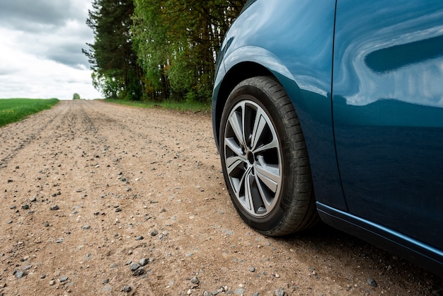 Car tire on gravel road near field.