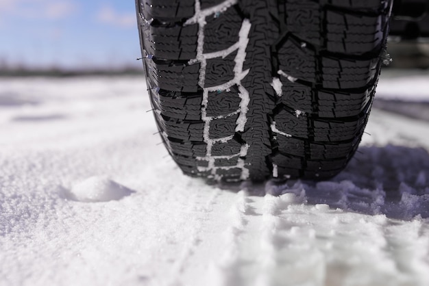 Car tires on winter snow road close up