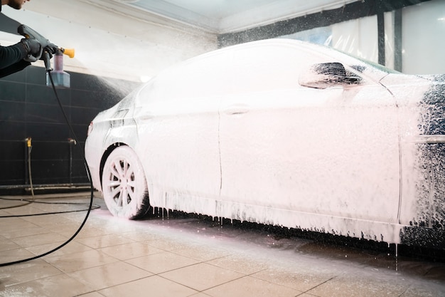 Car wash employee applies foam to the car.