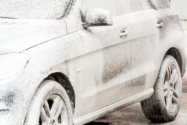 Car wash with foam in car wash station Carwash Washing machine at the station Car washing concept Car in foam