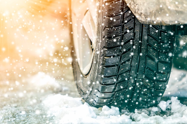 Ruota auto su una strada innevata e fiocchi di neve