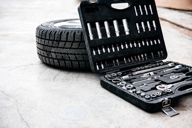 Photo car wheel with tools box on asphalt background.
