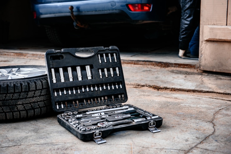Photo car wheel with tools box on asphalt background.