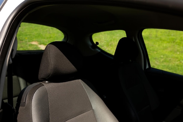 A car window with a black seat and a green grass in the background.