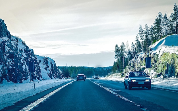 Photo car on winter road with snow in finland. auto and cold landscape of lapland. automobile on europe forest. finnish city highway ride. roadway and route snowy street trip. driving