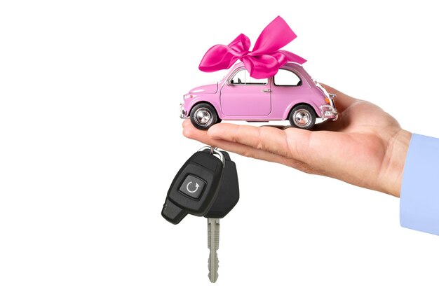 Car with bow and key on dealers hand isolated on white background. Car purchase concept