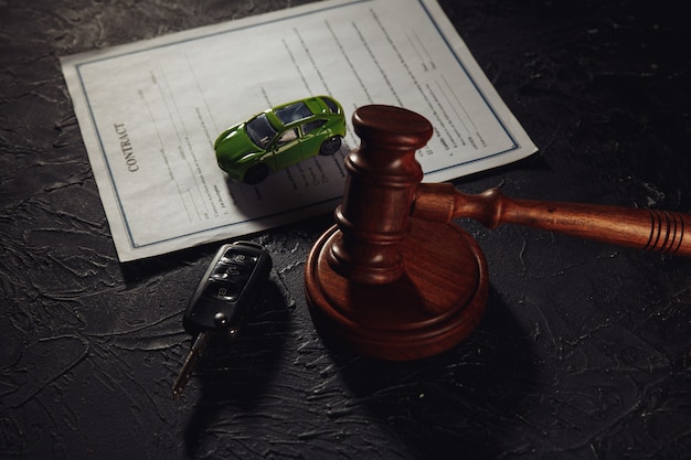 Car with keys on contract and wooden judge gavel.