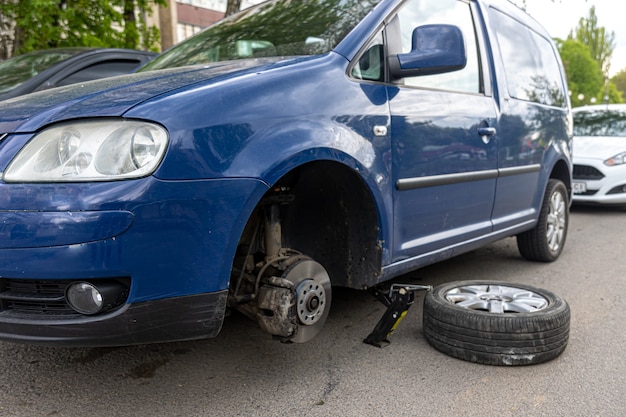 Car without wheel and lift up by hydraulic, waiting for tire replacement.