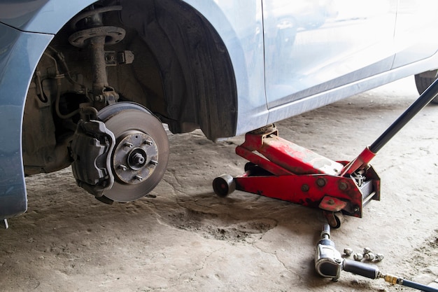 Car without wheel and lifted up by hydraulic waiting for tire replacement