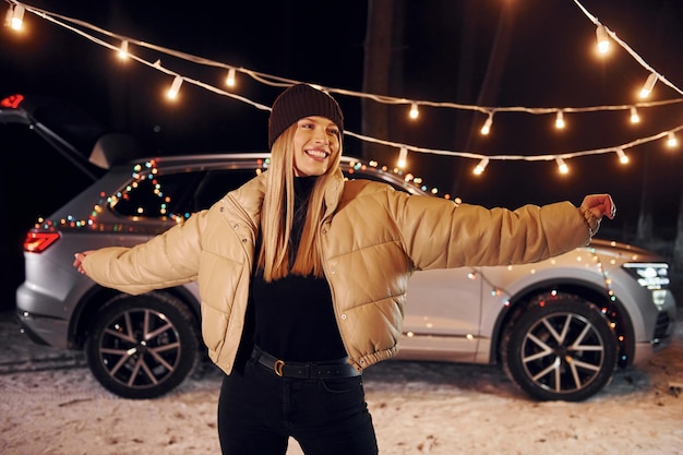 Car behind Woman standing in the forest and celebrating New year