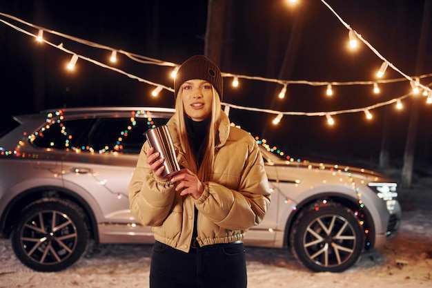 Car behind Woman standing in the forest and celebrating New year