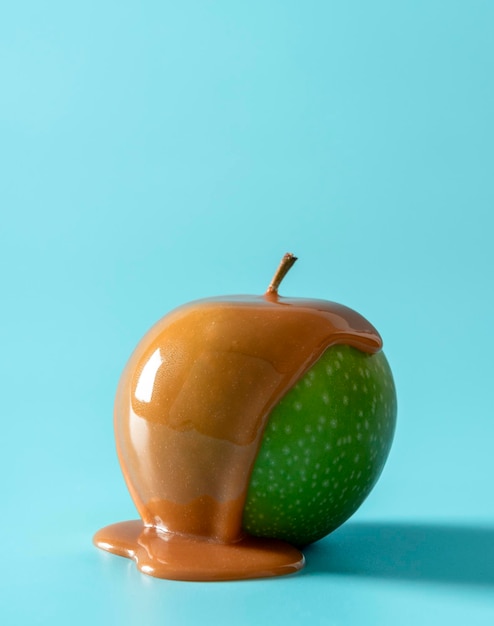 Caramel apple isolated on a blue background green apple covered in caramel sauce