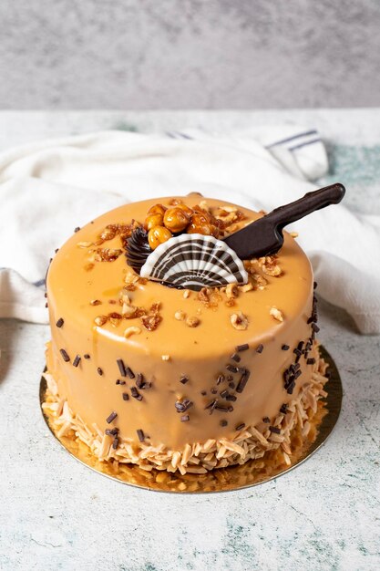 写真 灰色の背景のカラメルケーキ チョコレートとヘーゼルナッツの誕生日または祝賀ケーキ パン屋のデザート 垂直の近くの景色