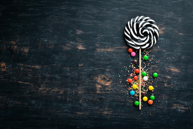 Caramel candies and lollipops Colored candies On a black background Top view free copying space