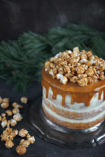 Torta al caramello con popcorn su sfondo scuro, messa a fuoco selettiva, verticale, festa di natale