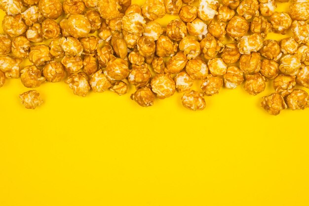Pop corn caramello su sfondo giallo spazio di copia