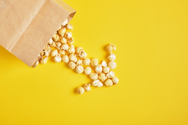 Caramel popcorn in een papieren zak op gele achtergrond