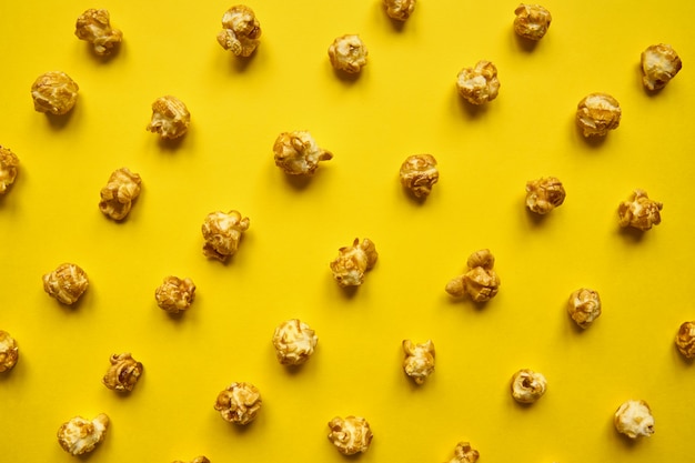 Caramel popcorn pattern on yellow background. Top view, monochrome concept