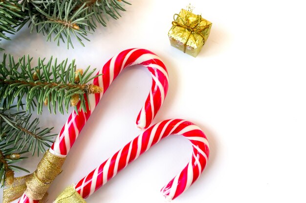 Caramel staffs with spruce branches and a gift box on a white background.