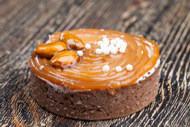 Photo caramel tartlet with milk cheese filling and lots of salted caramel with nuts, almonds on tartlets with cottage cheese or butter cream and caramel