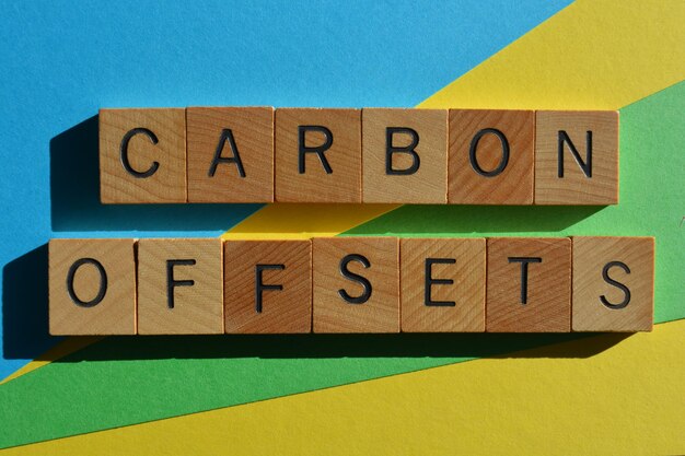 Carbon offsets words in wooden alphabet letters isolated on blue green and yellow background