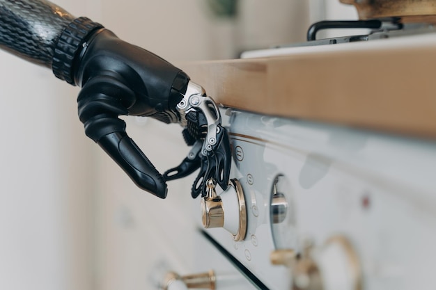 Carbon prothetische hand van gehandicapte zet een fornuis aan in de keuken Routine van gehandicapte