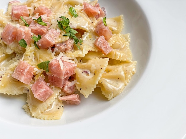 carbonara farfelle pasta with ham sausage on white plate