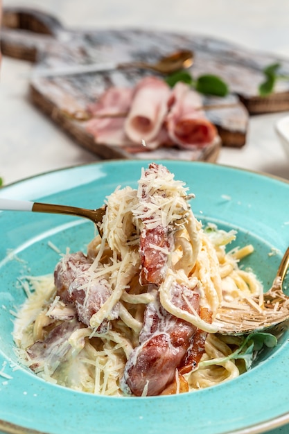 Foto pasta alla carbonara, spaghetti con pancetta, parmigiano e salsa di panna. pasta italiana. concetto di cucina, immagine verticale. copia spazio.