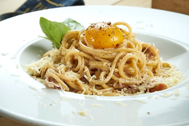 Carbonara pasta with yolk and parmesan with cream sauce. Italian traditional spaghetti for lunch. Delicious tasty close up. Food table. Selective focus