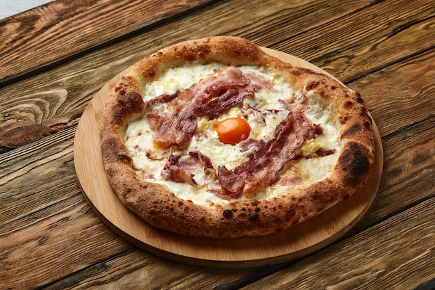 Пицца карбонара с беконом и яйцом на деревянном фоне