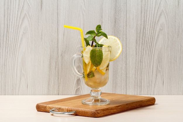 Limonata gassata con fette di limone e menta su un tagliere di legno, bevanda fredda per una calda giornata estiva