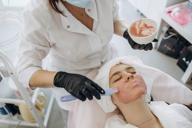 Carboxytherapy for the face Almond face peeling Beautician applies a cleansing face mask to the patient Face peeling at the beautician Facial treatments Photo chemical glycolic almond peeling