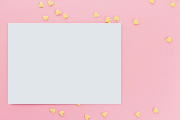 card on a background of heart-shaped confectionery confetti on a pink background copy space. Yellow hearts