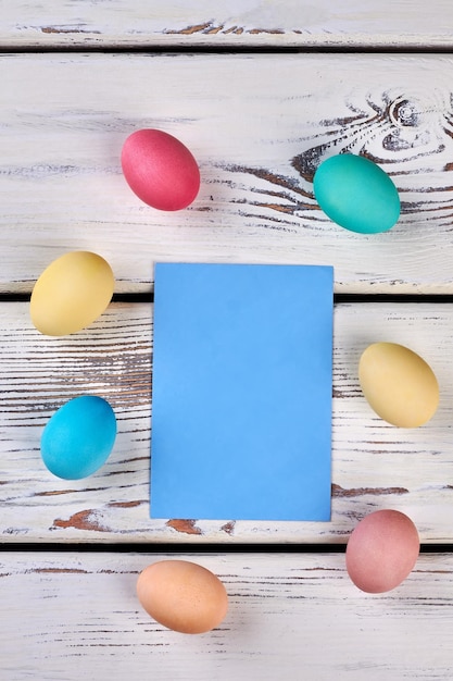 Carta di uova di pasqua sullo sfondo di legno carta blu vuota ricorda le tradizioni