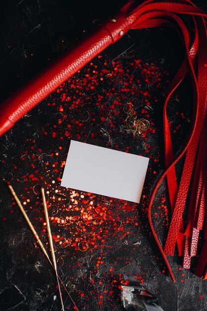 card mockup, mockup of a white sheet of paper bdsm toys, red leather whip on a black background with