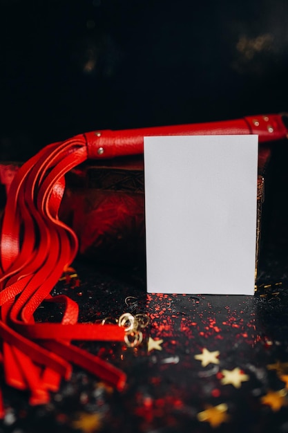 card mockup, mockup of a white sheet of paper bdsm toys, red leather whip on a black background with